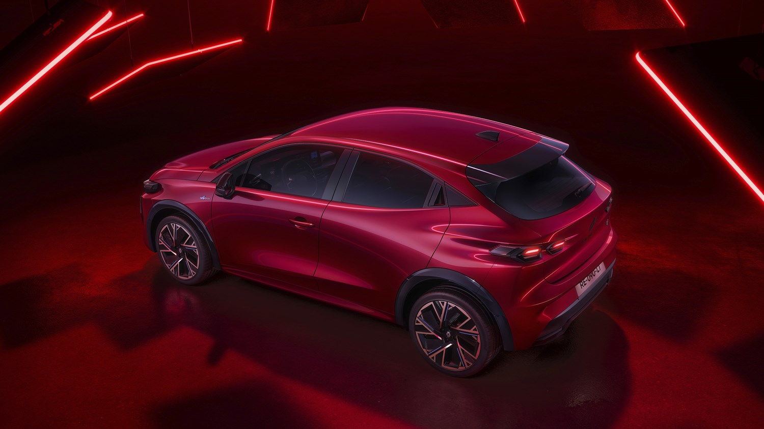 Rdeče vozilo Clio v studijskem prostoru z bordo rdečim ozadjem.