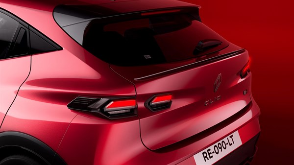 Bližnji pogled na zadnji del rdečega Renault Clio s zadnjimi LED lučmi in spojlerjem.