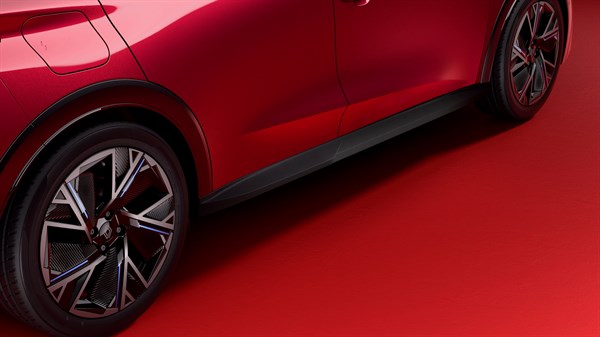 Spodnji del rdečega Renault Clio, prikaz strani z zadnjim kolesom in stransko zaščito pragov.