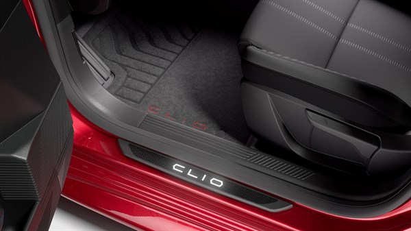Odprta zadnja vrata rdečega vozila, vidna je osvetljena vstopna letev z napisom Clio ter tekstilne in gumijaste preproge na tleh kabine.