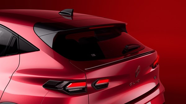 Rdeč Renault Clio, zgornji zadnji tričetrtinski pogled; vidno zadnje okno in luči v rdečem studiu.