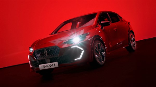 Rdečo Renault Clio v temnem okolju z osvetlitvijo, ki poudari njegov dizajn in linije.