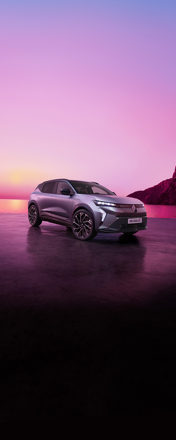 Renault Scenic E-Tech electric v srebrni barvi parkiran ob morju ob sončnem zahodu z rožnatim nebom v ozadju.