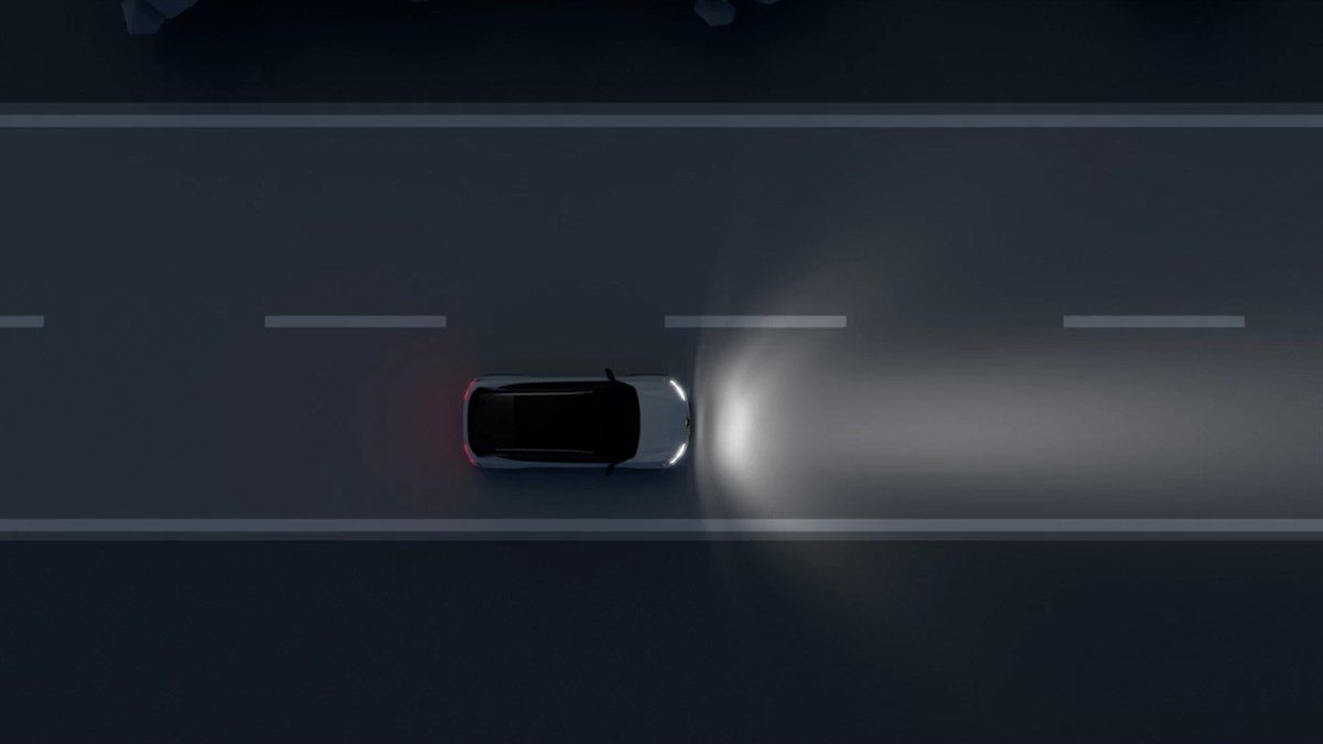 Renault Scenic E-Tech electric v temni barvi, pogled od zgoraj, vozi po cesti ponoči z vključenimi žarometi, ki osvetljujejo vozišče pred vozilom.