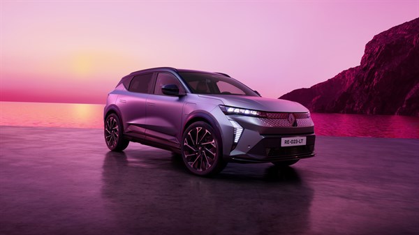 Renault Scenic E-Tech electric v temno sivi barvi parkiran ob obali ob sončnem zahodu z rožnatim nebom in skalnato obalo v ozadju.