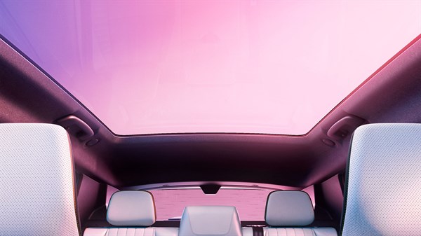 Pogled iz notranjosti vozila na odprto panoramsko stekleno streho s sedeži v ospredju.