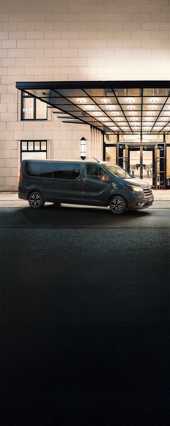 Slika prikazuje vozilo Renault Trafic SpaceClass parkirano pred elegantnim hotelom. Gre za nočni prizor, ki poudarja prefinjenost in prestižen značaj vozila – idealno za poslovne in VIP prevoze.