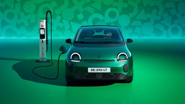 Zeleni Twingo priključen na polnilnico, sprednji pogled, na zelenem studijskem ozadju.