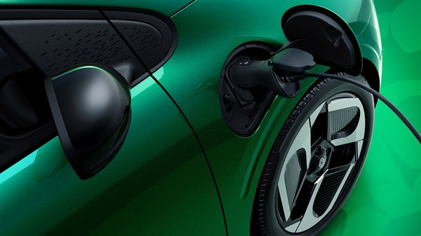 Detajl polnjenja zelenega vozila Twingo, priključen polnilni kabel v polnilni vtičnici ob sprednjem kolesu.