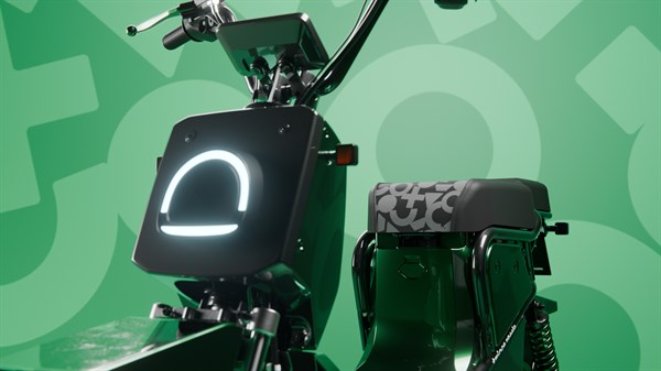 Bližnji posnetek sprednjega dela črno-zelenega skuterja z osvetljenim sprednjim panelom in sedežem.