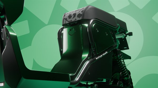 Bližnji posnetek zadnjega dela črno-zelenega skuterja s sedežem z vzorcem ter zadnjim blažilnikom na zelenem ozadju.