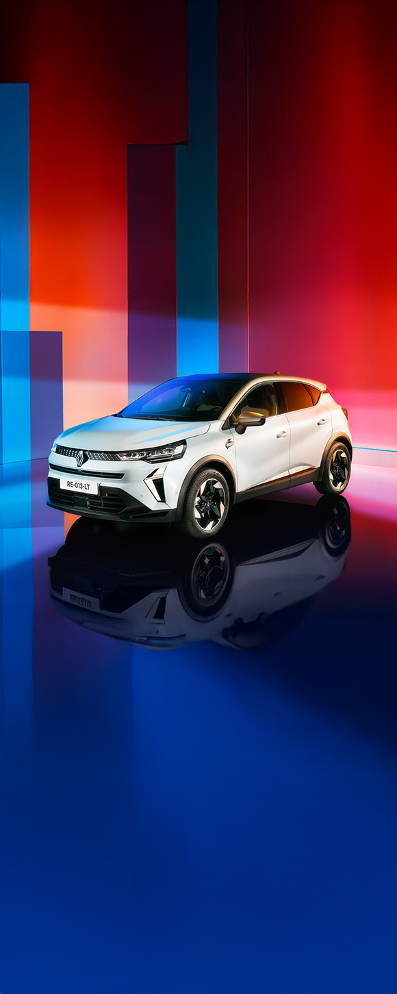 Renault Captur osvetljen v studijskem okolju z večbarvnim ozadjem, viden s sprednje leve strani.