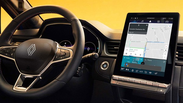 Notranjost vozila z osrednjim navpičnim zaslonom, ki prikazuje navigacijski sistem z zemljevidom in načrtovano potjo.