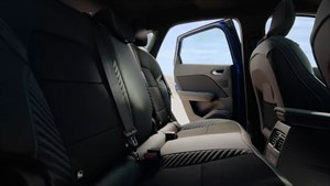 Zadnji sedeži vozila, pogled s strani skozi odprta zadnja vrata, vidna sta črna oblazinjenja z modrimi šivi.