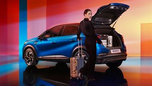 Modri Renault Captur z odprtim prtljažnikom – spredaj stoji ženska s kovčkom.