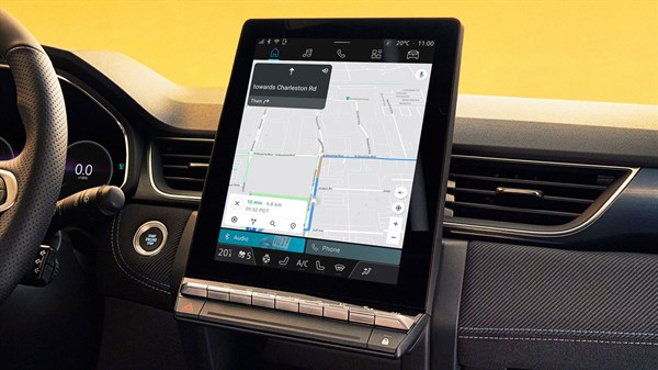 Notranjost vozila z osrednjim navpičnim zaslonom, ki prikazuje navigacijski sistem z zemljevidom in načrtovano potjo.