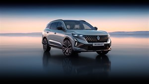 Renault Espace parkiran na odsevni površini ob sončnem zahodu.