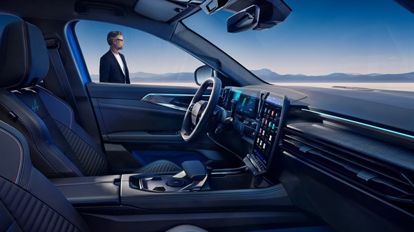 Pogled iz notranjosti Renault Rafale na digitalni zaslon in voznikov prostor, z moškim, ki stoji zunaj ob vozilu.