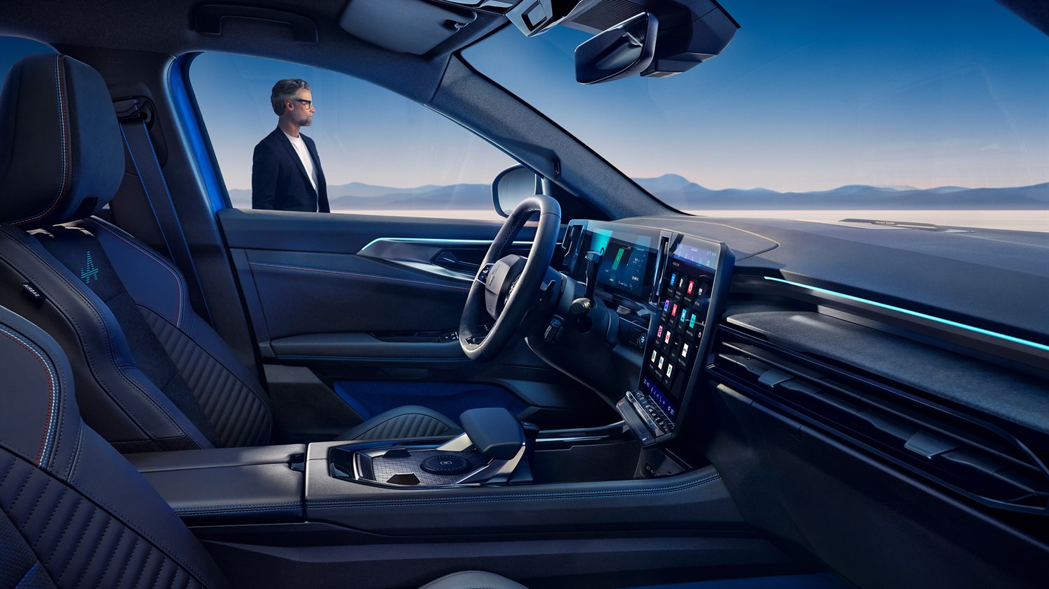 Pogled iz notranjosti Renault Rafale na digitalni zaslon in voznikov prostor, z moškim, ki stoji zunaj ob vozilu.