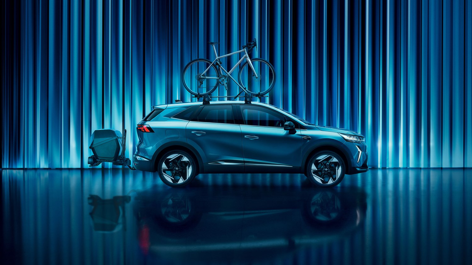 Modri Symbioz z nameščenim kolesom na strehi in kovčkom na zadnjem delu.