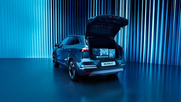 Renault Symbioz osvetljen z modro svetlobo z odprtim prtljažnikom s kovči.