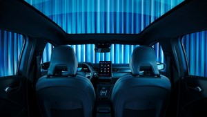 Pogled iz zadnjih sedežev vozila Renault Symbioz proti armaturni plošči, z odprtim panoramskim steklenim strešnim oknom in osrednjim digitalnim zaslonom na dotik.