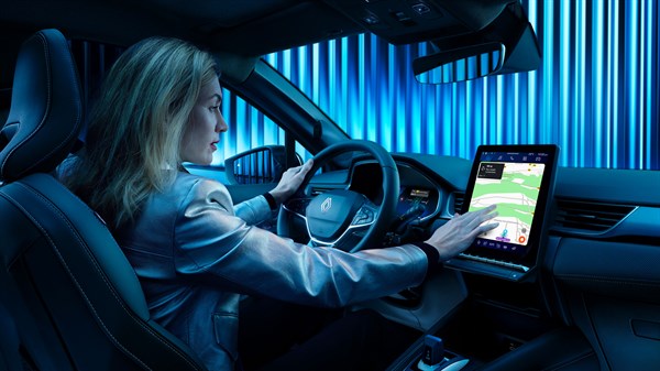 Ženska sedi za volanom Renault Symbioz in upravlja osrednji zaslon na dotik.
