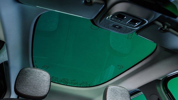Renault Twingo E-Tech electric - pogled iz notranjosti na stekleno streho z zelenim odsevom nad sprednjima sedežema.