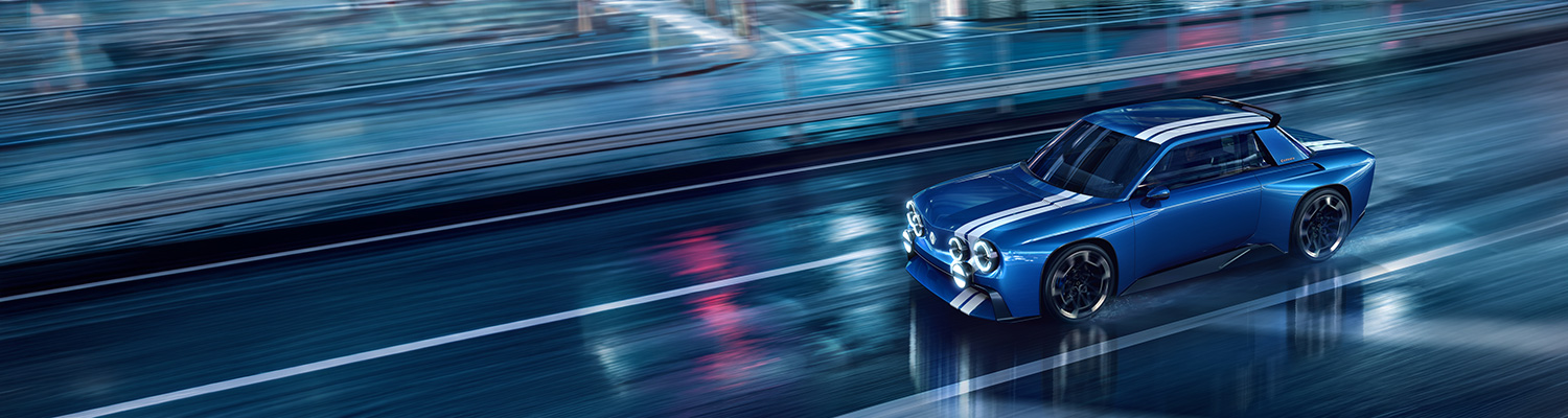 Renault 8 Gordini Concept v modri barvi z dvojno belo progo, sprednji tričetrtinski pogled med vožnjo po mokri cesti ponoči