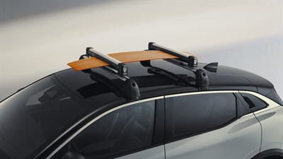 Renault Megane E-Tech Electric s pritrjenim strešnim nosilcem in nameščeno desko za deskanje v studijskem okolju.