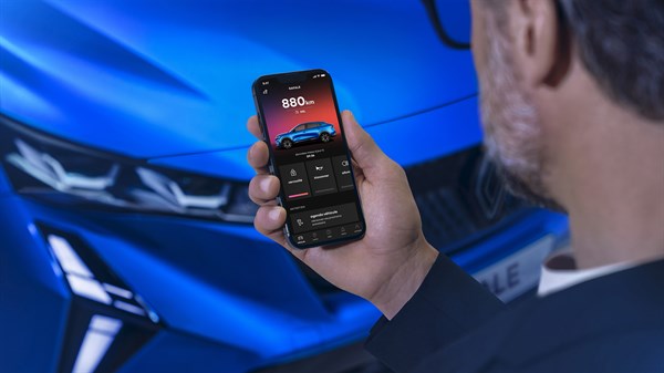 Moški v roki drži pametni telefon, ki prikazuje status vozila Renault.