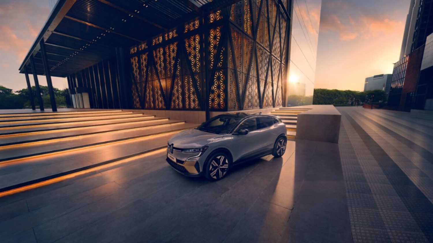 Ženska v rdeči opravi teče mimo srebrnega vozila Renault Clio, parkiranega pred turkizno stavbo.