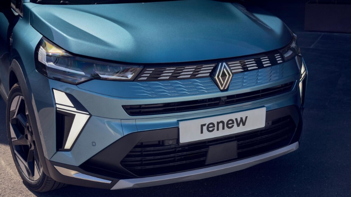 Družina ob hiši z odprtim prtljažnikom Renault vozila.
