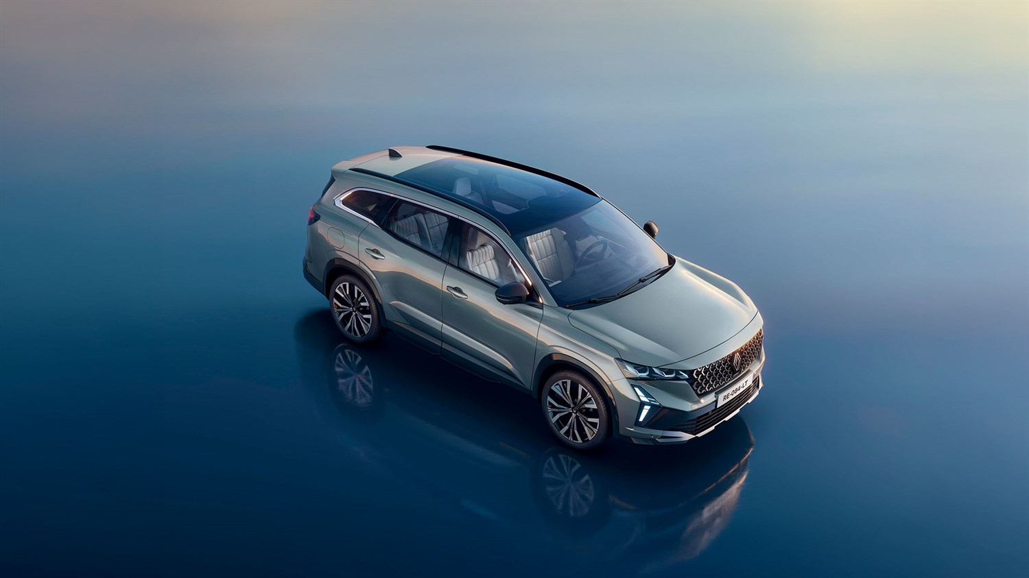 Renault SUV iz bočne strani, parkiran na odsevni površini ob sončnem zahodu.